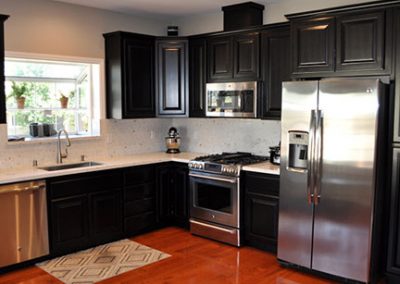 kitchen with stainless steel appliances and dark wood custom cabinets
